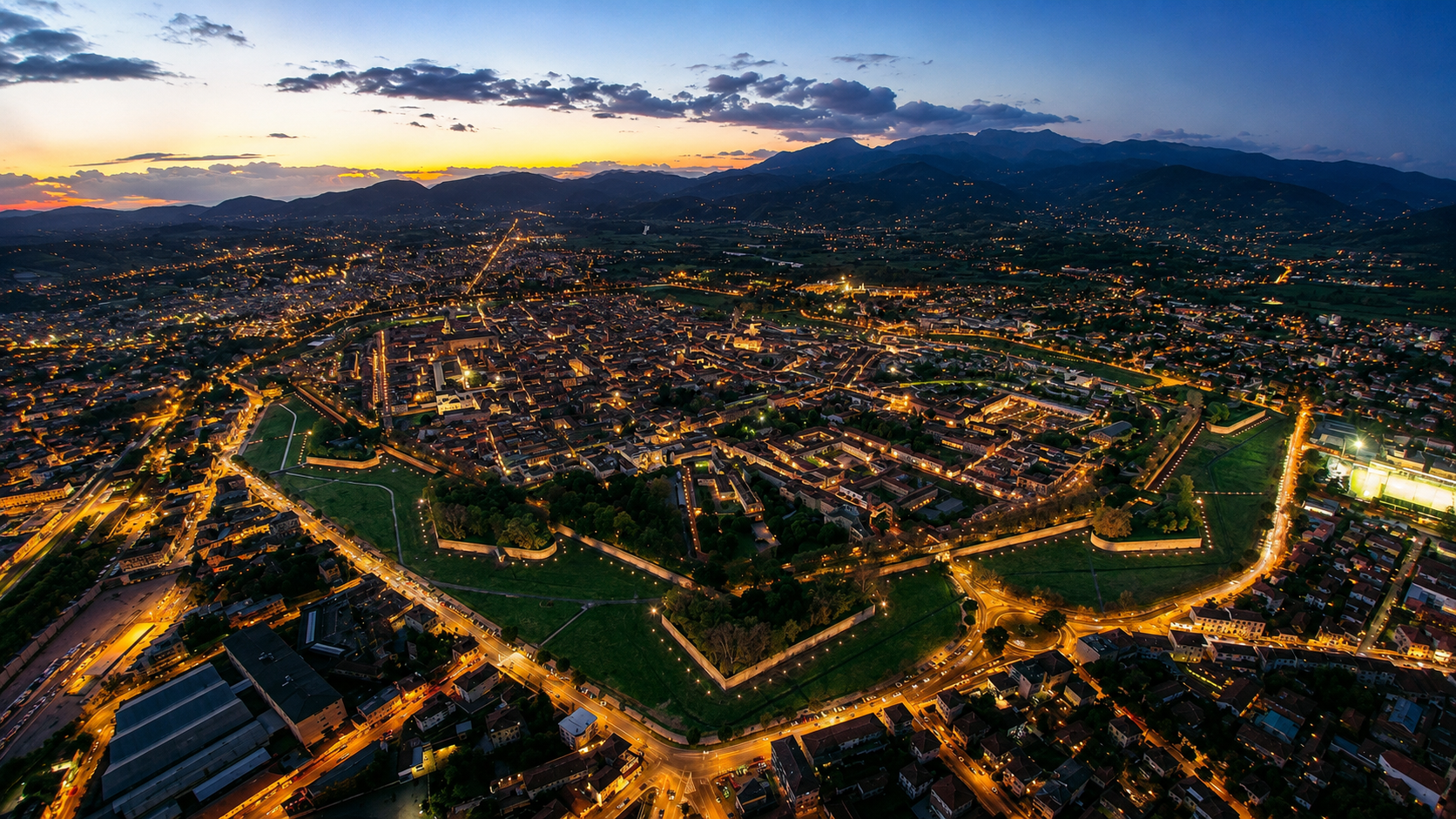 Vista aerea panoramica di Lucca al tramonto con le mura storiche e il centro città illuminato